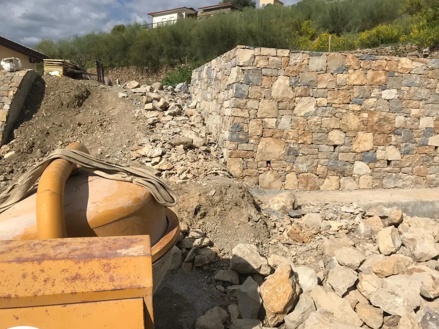 Cantiere edile a Vallebona con betoniera e muro di contenimento in pietra in costruzione, preparazione del terreno per villa in Costa Azzurra.