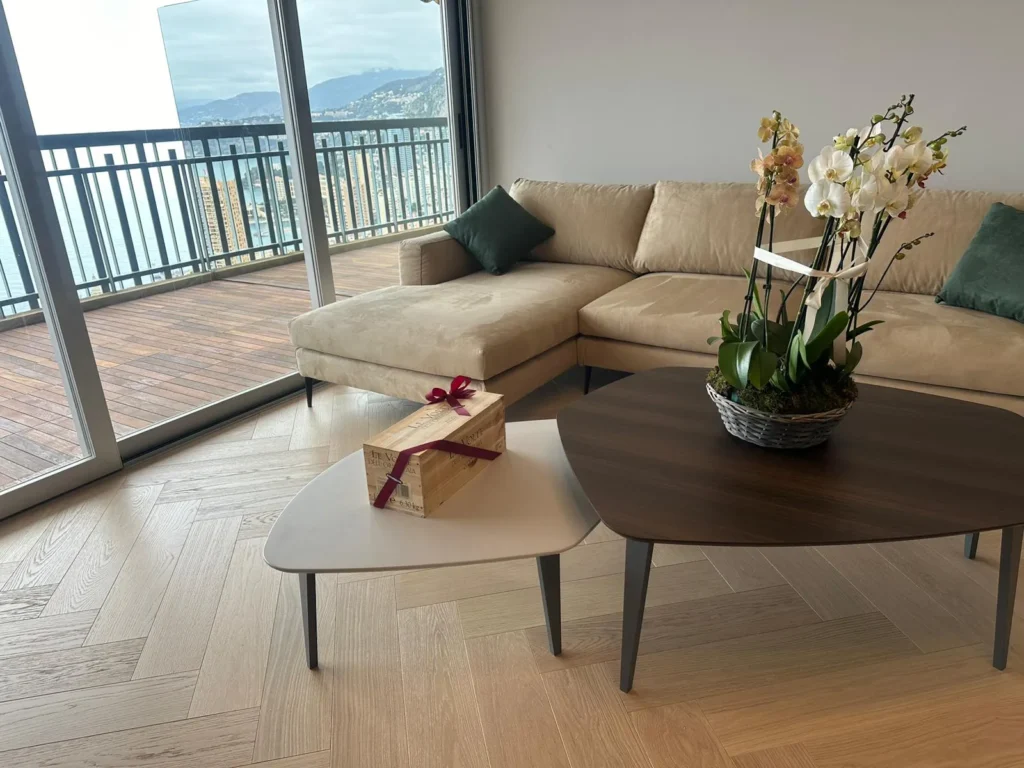 Salone moderno di lusso con vista panoramica a Monte-Carlo, divano angolare e tavolini di design, arredamento curato da impresa edile specializzata tra Ventimiglia e Cap-d'Ail.