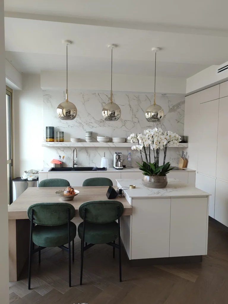 Cucina moderna lussuosa con tavolo da pranzo integrato, finiture in marmo e illuminazione di design, esempio di ristrutturazione a Roquebrune-Cap-Martin da impresa edile Ventimiglia.