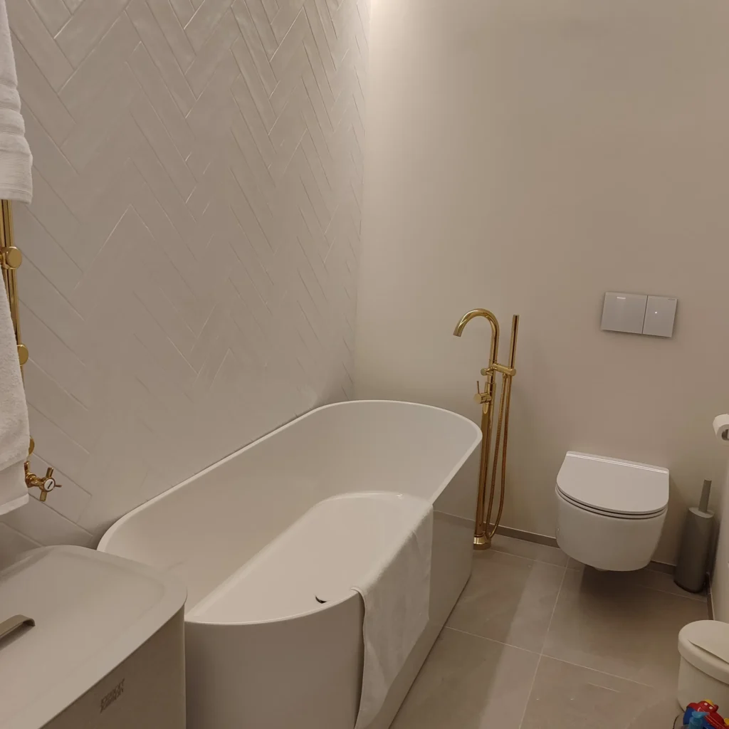 Bagno di lusso con vasca freestanding di design, rubinetteria dorata e sanitari sospesi. Concediti il massimo del relax e dell'eleganza con le nostre ristrutturazioni complete a Sanremo, Bordighera e Ventimiglia.